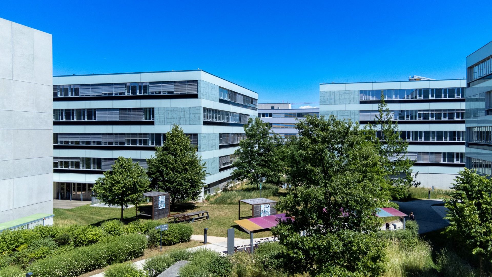 Vue aérienne de l'EPFL Innovation Park: plusieurs bâtiments, des pelouses, des arbres et des sentiers © EPFL innovation Park