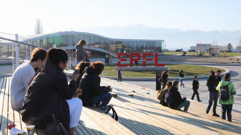 Vue de la place Cosandey depuis l'Agora Lombard Odier. Des étudiantes et des étudiants tranquillement assises et assis sur les marches. Au second plan, le logo EPFL et le Rolex learning Center © Alain Herzog, EPFL 2020