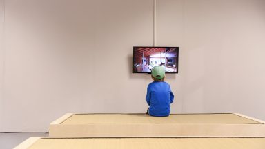 © EPFL - Alain Herzog Un enfant, de dos, face à un écran dans ue grande salle vide d'Archizoom, durant la Nuit des Musées 2015