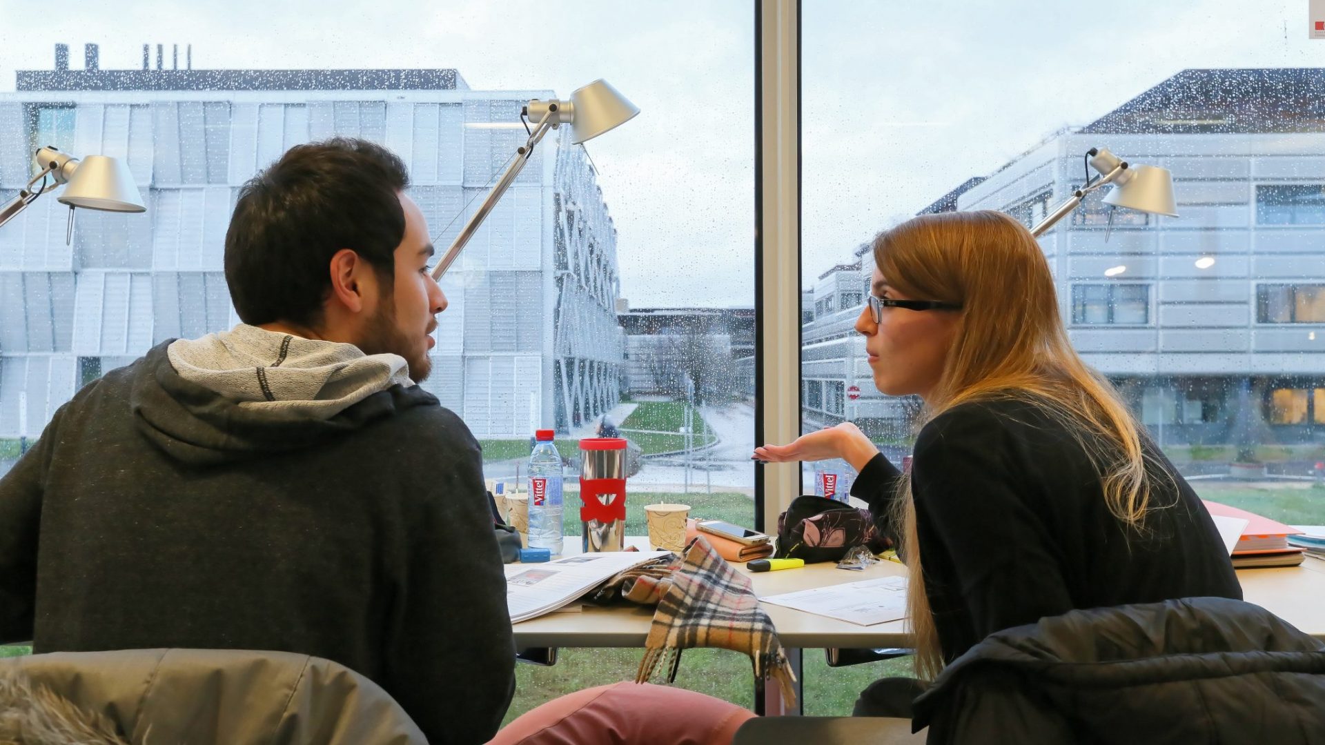 Des Ă©tudiants discutant devant une fenĂȘtre du Rolex Learning Center, en rĂ©visant leurs examens