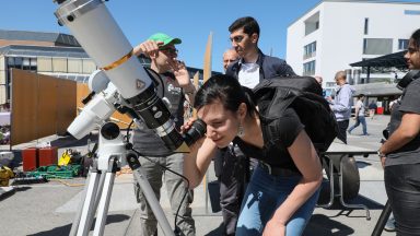 Des étudiants scrutent le ciel à l'aide d'un petit télescope installé sur la place de l'esplanade du campus.